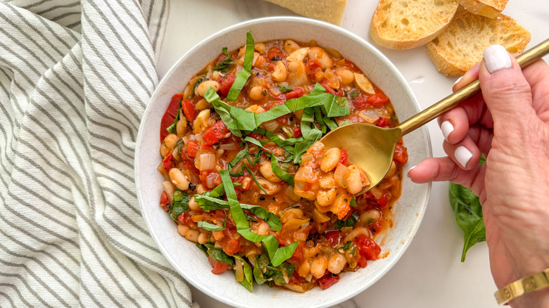 hand holding spoon over bean dish