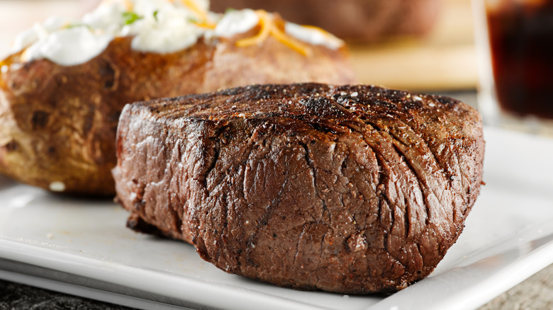 A steak and baked potato on a plate