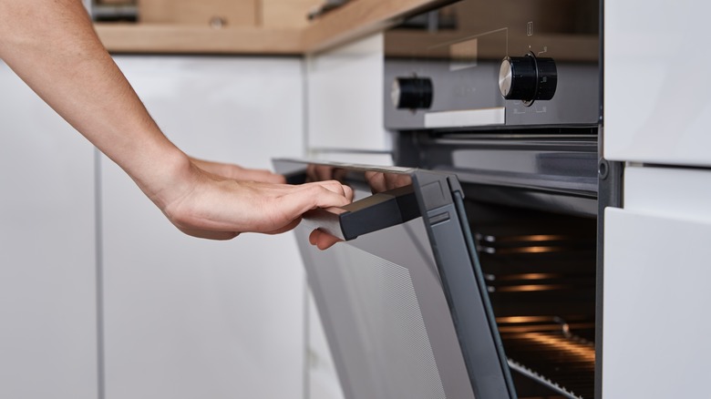 hand opening an electric oven