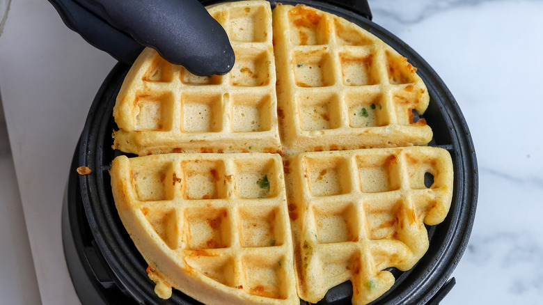 a cooked waffle being taken out of a waffle iron