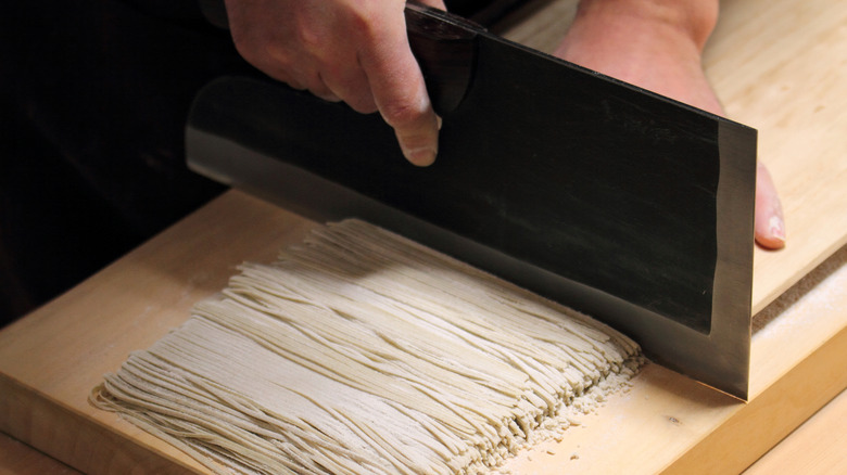 Chef cutting raw soba noodles