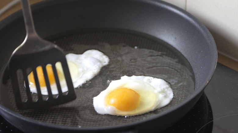 frying egg in pan with spatula