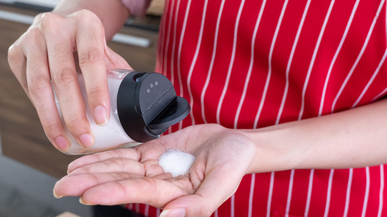 Person pouring salt into hand