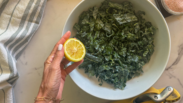 hand adding lemon to kale