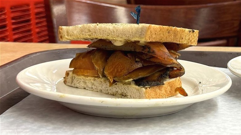 Katz's x Row 7 vegetarian "pastrami" sandwich on table with pickles