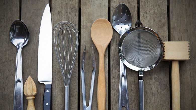 Top-down view of various kitchen tools on a wooden deck