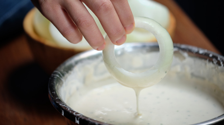 Hand holding onion in batter