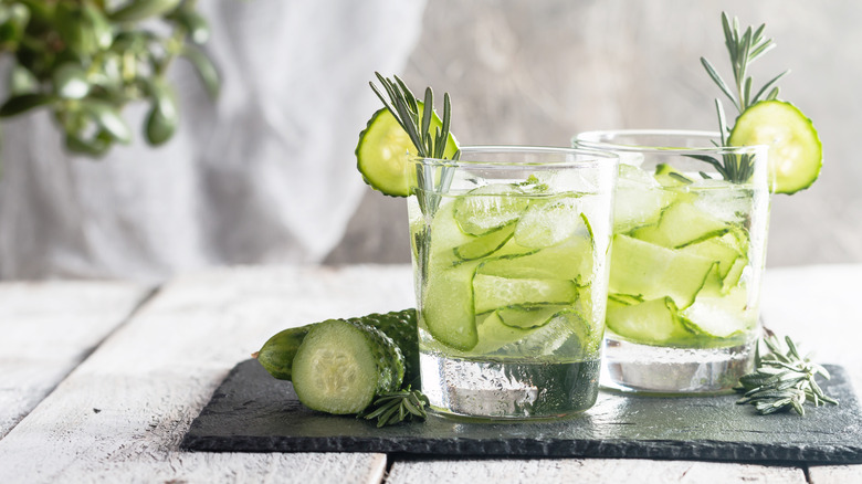 Two glasses with slices of cucumber.