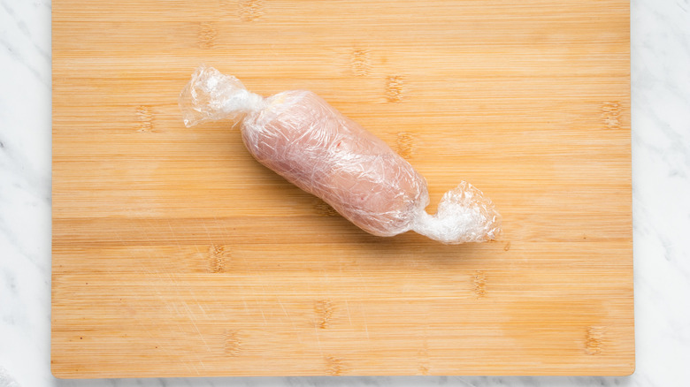 chicken wrapped on cutting board 