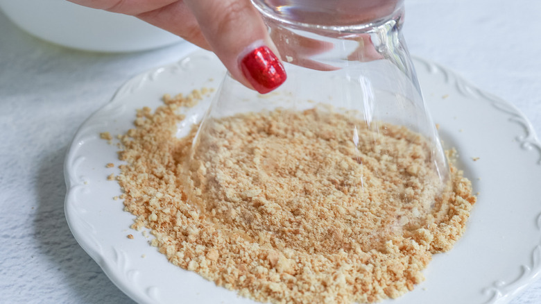 glass dipping into graham cracker crumbs