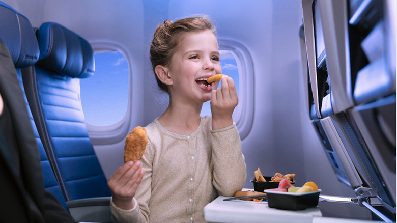 kid on plane eating chicken