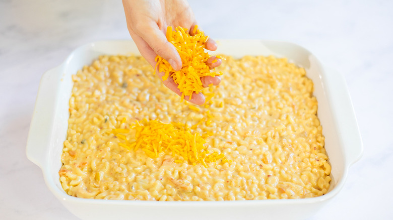 sprinkling cheese onto mac and cheese