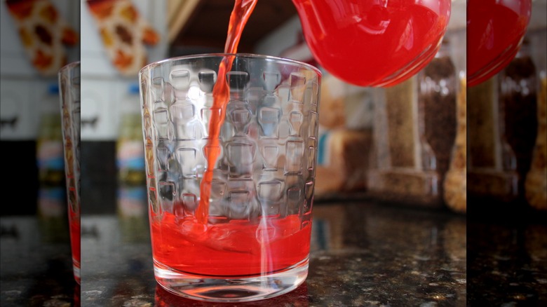 Pouring red Kool-Aid into a glass