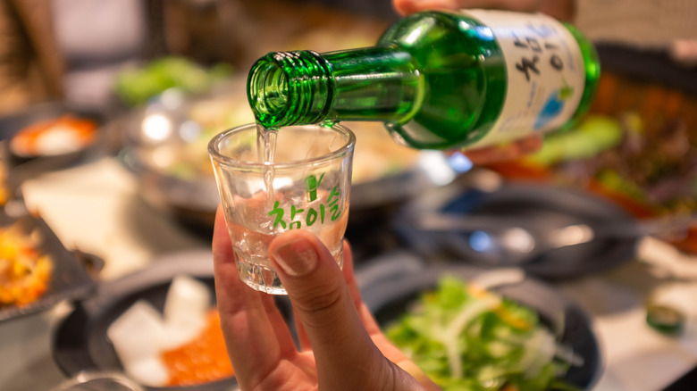 hand pouring glass of soju