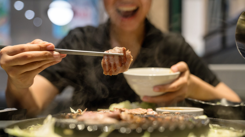 chopsticks grabbing meat off grill