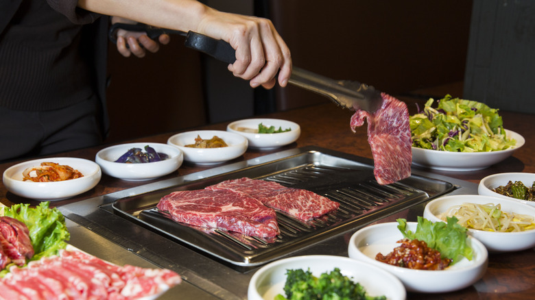 person grilling meat on korean bbq