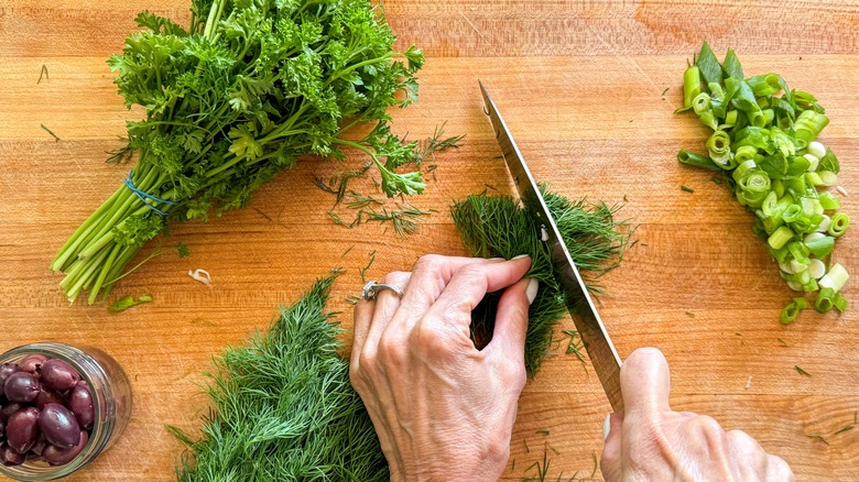 hand cutting dill on board