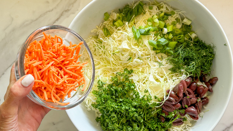 hand adding carrots to bowl