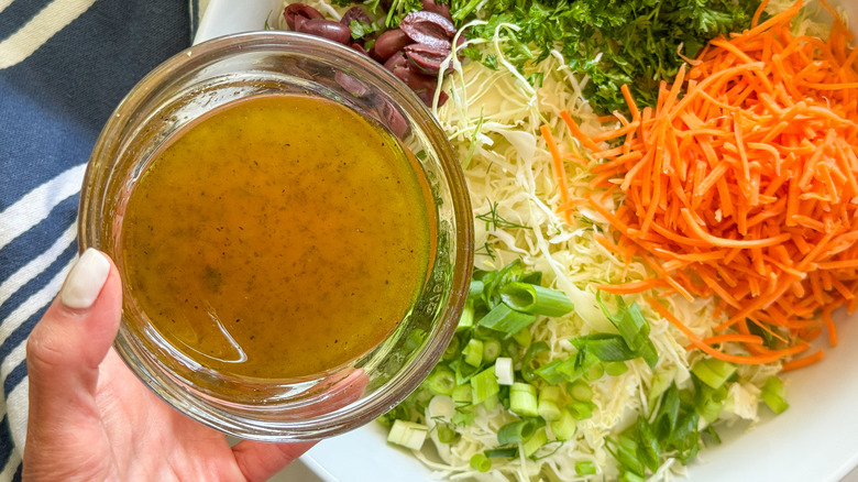 hand adding dressing to salad