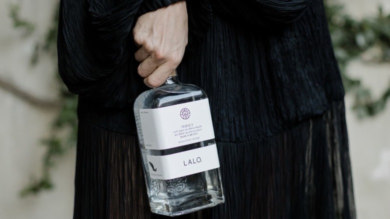 Bottle of Lalo held against black dress