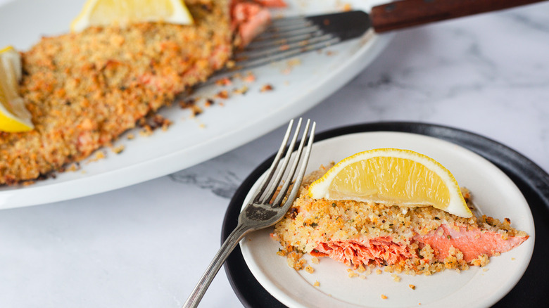 breadcrumb crusted salmon on white plates with lemons