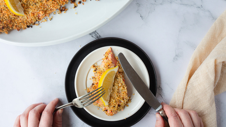 breadcrumb crusted salmon on white plate with lemon