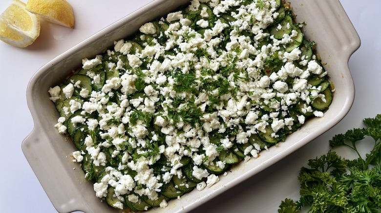 layered zucchini casserole with lemon wedges and parsley sprig