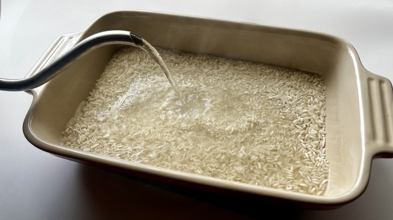 spout pouting boiling water over white rice in a baking dish