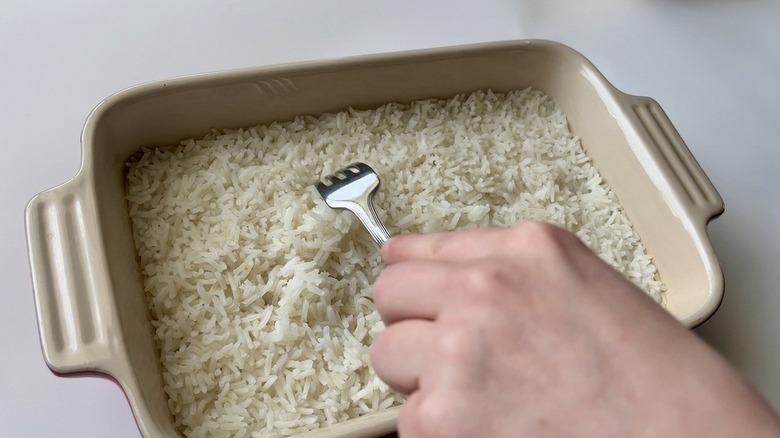 hand fluffing white rice with a fork