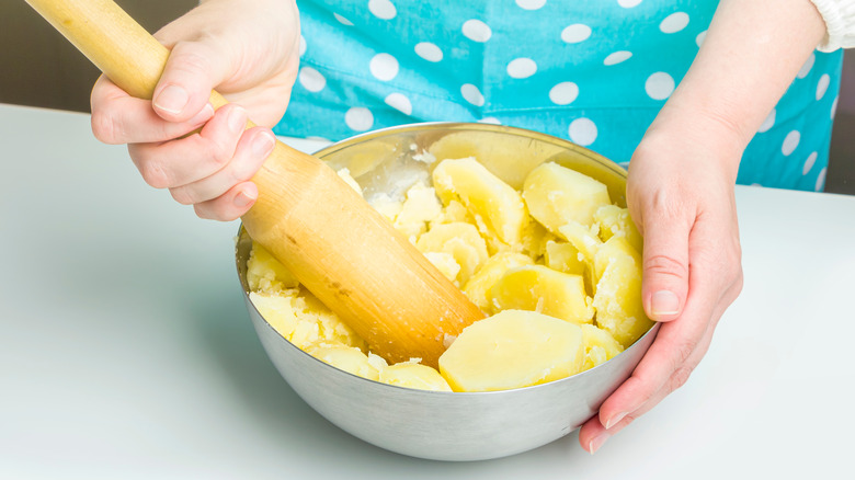 woman mashing potatoes in bowl