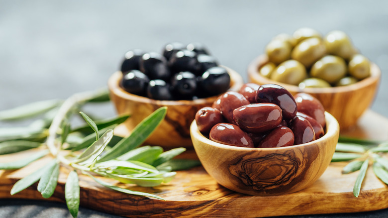 three bowls of olives on wooden board