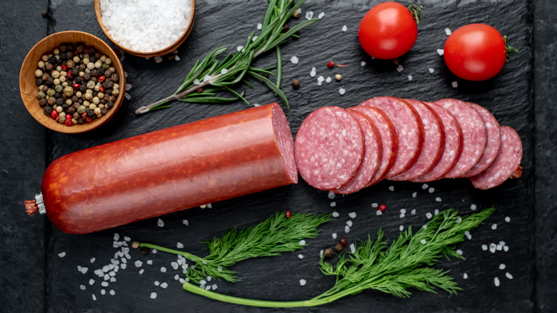 sliced sausage near tomatoes and herbs