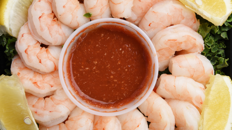 Overhead view of a cocktail sauce surrounded by prawns