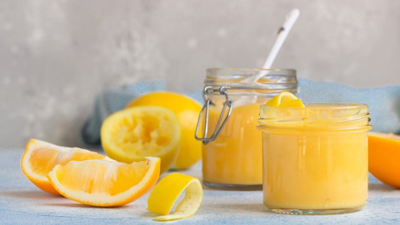 Jars of lemon curd next to citrus wedges