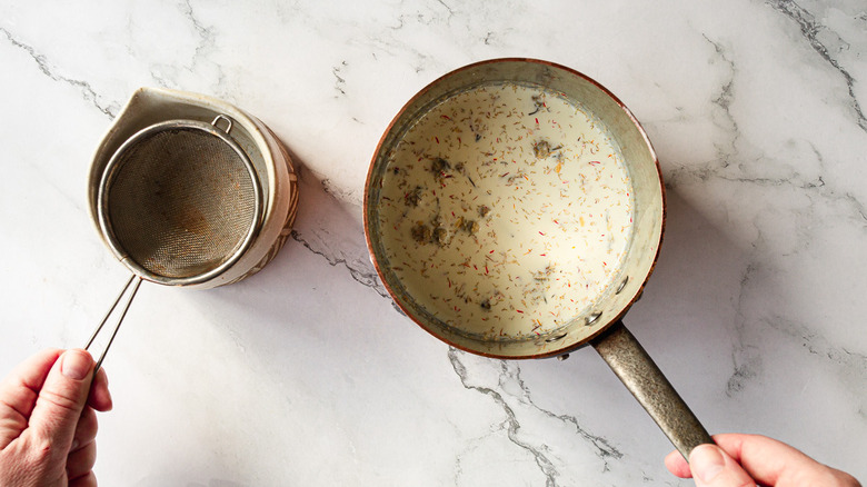 hands holding sieve and saucepan