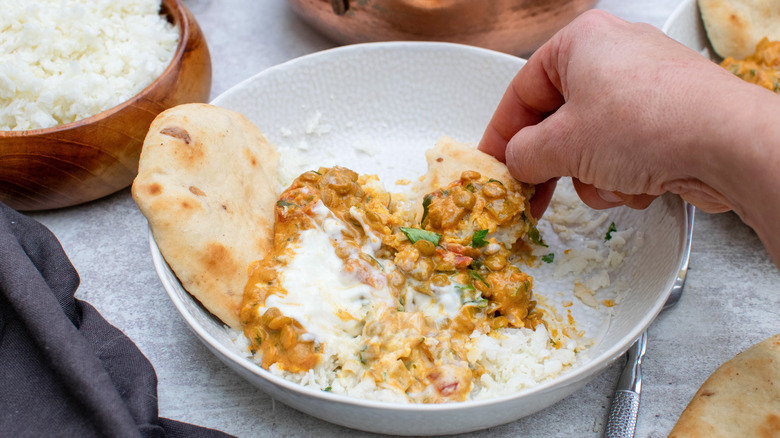 Bowl of lentil curry with hand