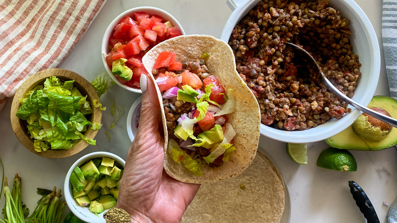 filling tortilla with lentil mixture and toppings