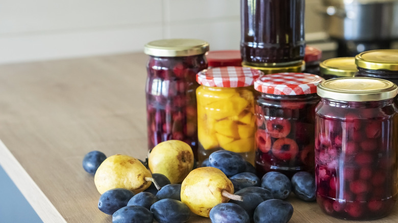 Various canned fruits, fresh plums, and pears