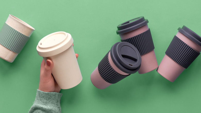 hand holding travel coffee mug