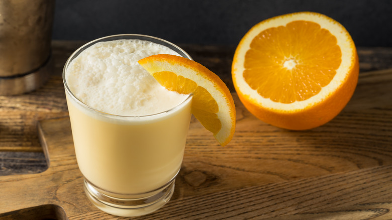 Frothy orange drink with orange wedge 