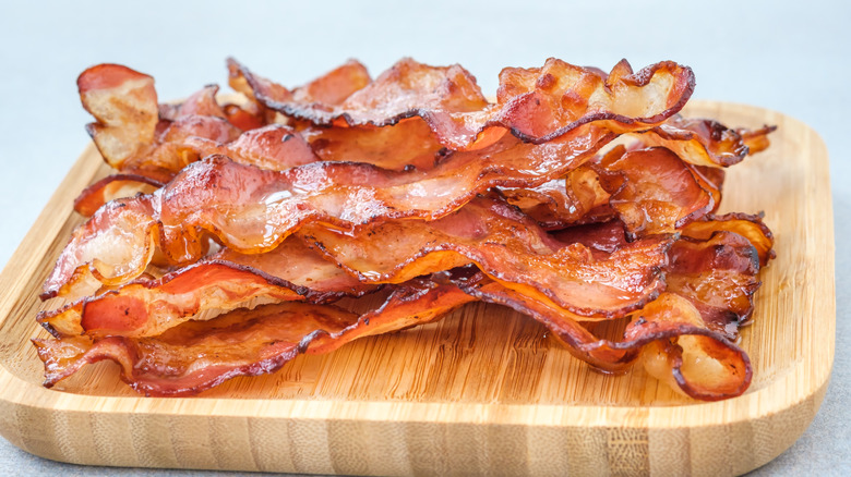 Crispy bacon pile sits on wooden board 