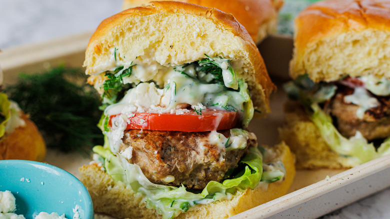 Two burgers with feta, dill and tomatoes