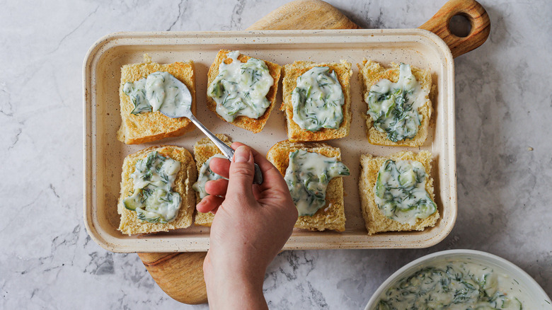 Spreading tzatziki on the buns