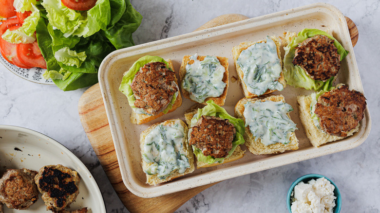 A baking sheet with four sliders with toppings