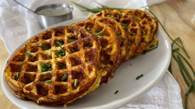 cheese waffles on white plate with bowl of sour cream