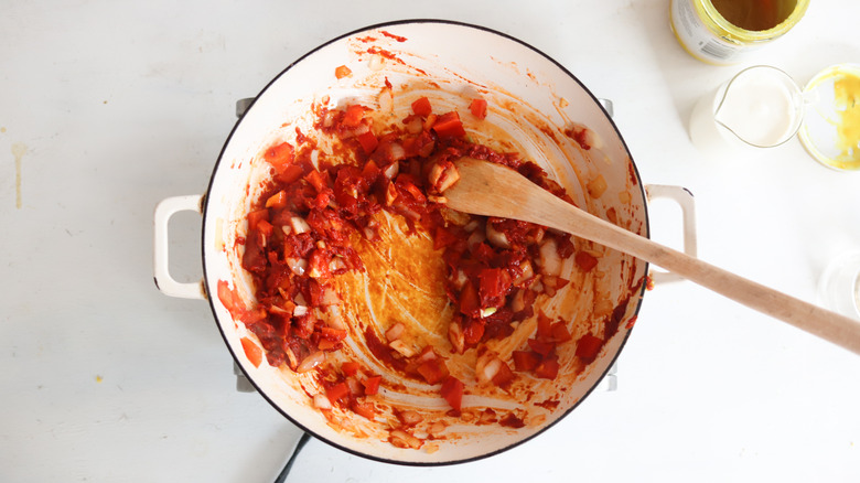 tomato paste in a pan with vegetables and wooden spoon