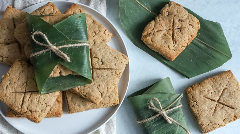 Pieces of square brown bread with some wrapped in green leaves