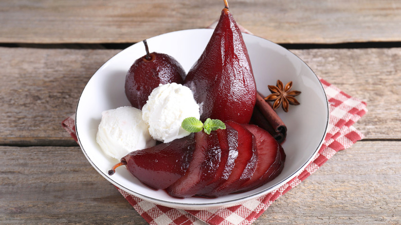 red wine poached pears and ice cream in bowl on wooden table, closeup