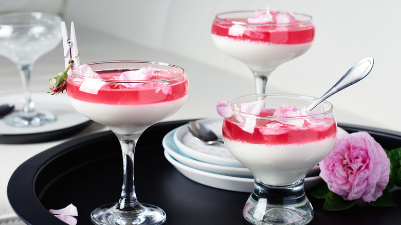 Vanilla panna cotta dessert with rose petals in elegant stemmed glasses