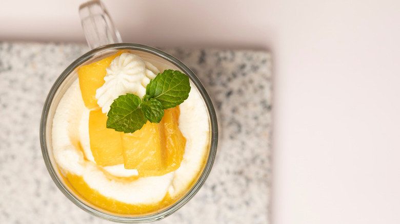 Mango sorbet float with whipped cream in a glass with mint garnish